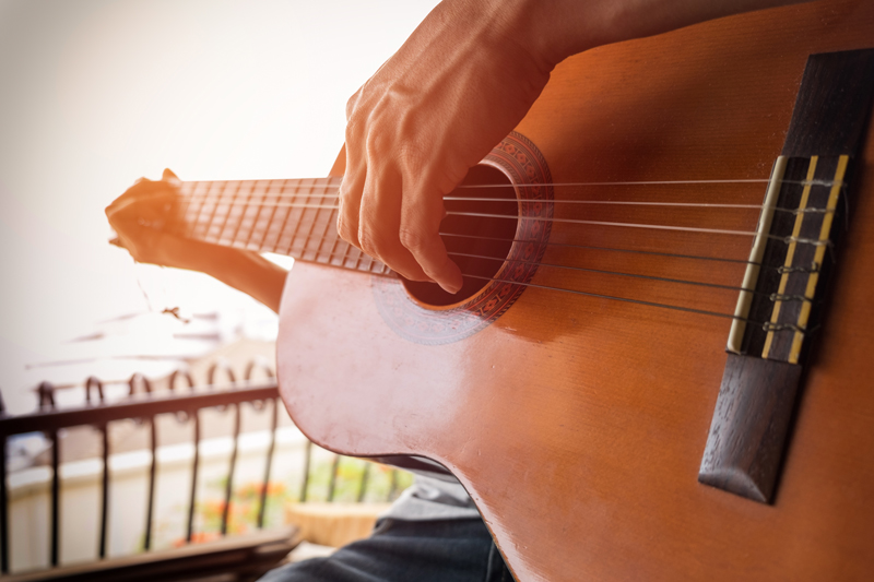 Close up of guitarist playing acoustic guitar