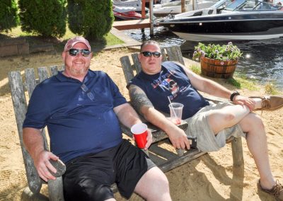 Two guys hanging on on the beach in Adirondack chairs.