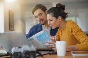 A young couple sits near their laptop planning their New Hampshire summer vacation.