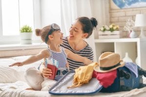A young mother and her daughter smile as they prepare their travel packing list for a Lake Winnipesaukee vacation.